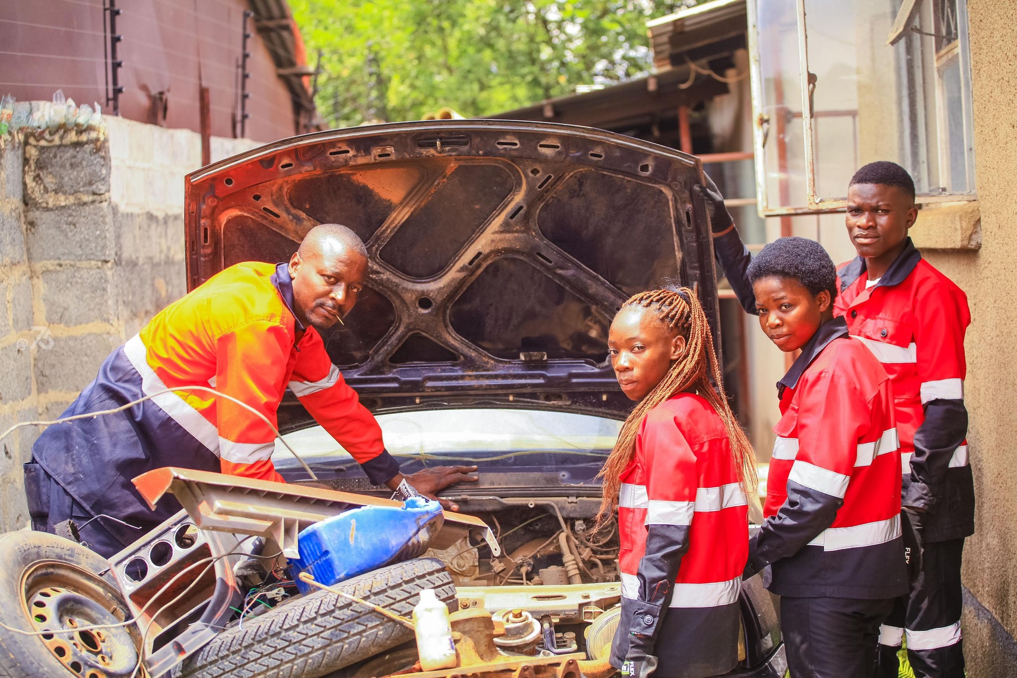 Students and instructor at an automotive workshop working on a car engine